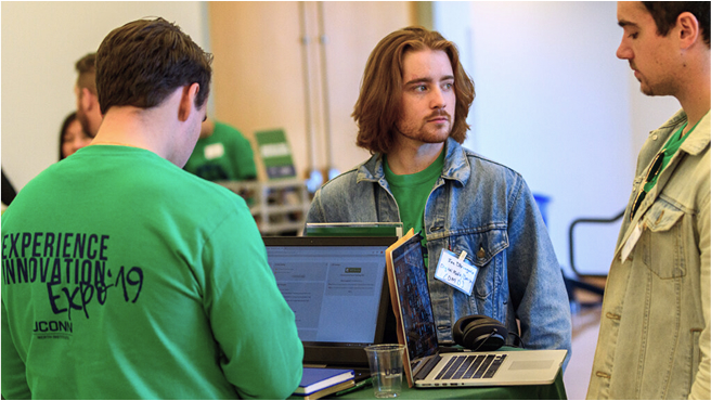 Three people standing with laptop on a bistro table