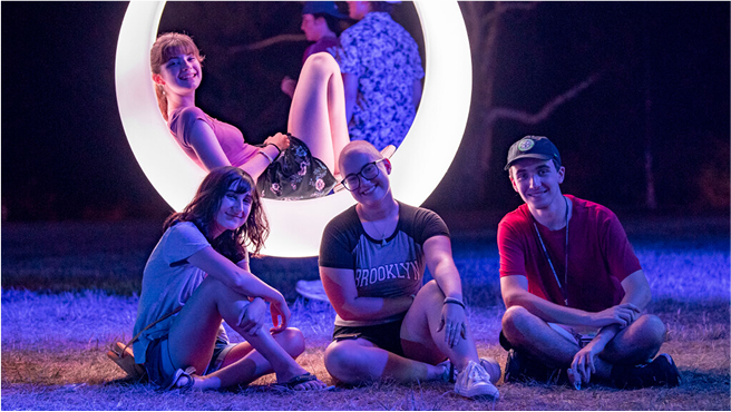Four students sitting around UConn glow swings