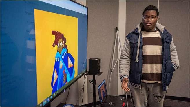 Student standing in front of tv monitor presenting a digital design